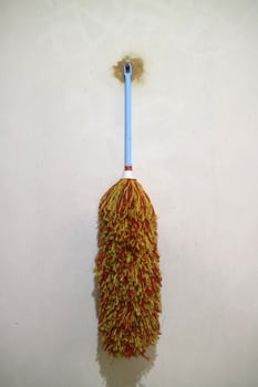A duster with red yellow feathers, hangs on the wall photo