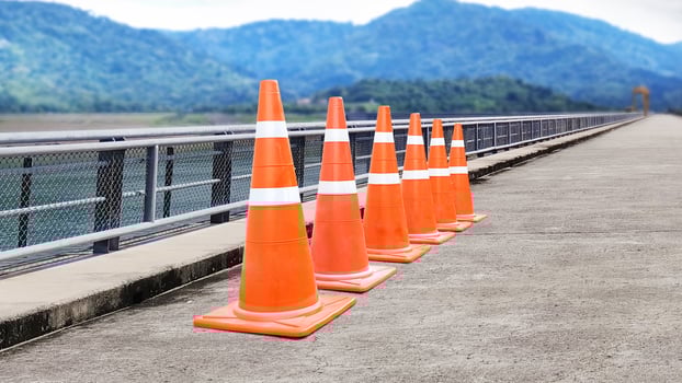 Orange traffic cone placed on cement road There is a mountain in the background. photo