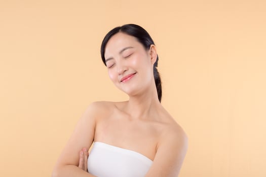 beauty asian young woman model with fresh glowing hydrated facial skin. girl person with natural makeup and healthy skin portrait isolated on beige studio background. spa treatment, skin care concept. photo