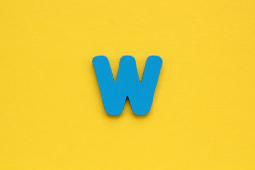 Wooden blue letter W on yellow background. Alphabet concept photo