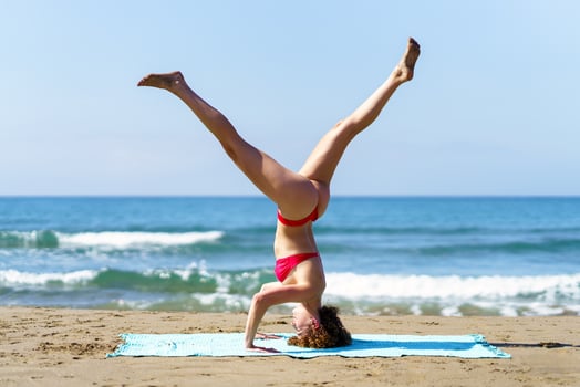 Healthy woman doing yoga on sandy coast photo
