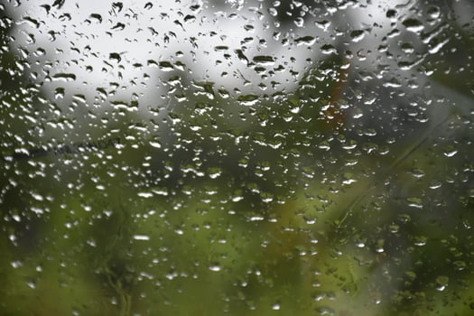 Blurred image of raindrops on the rear view mirror of car, soft focus photo