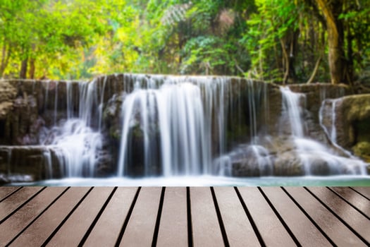 Wood table top on blurred waterfall deep forest photo