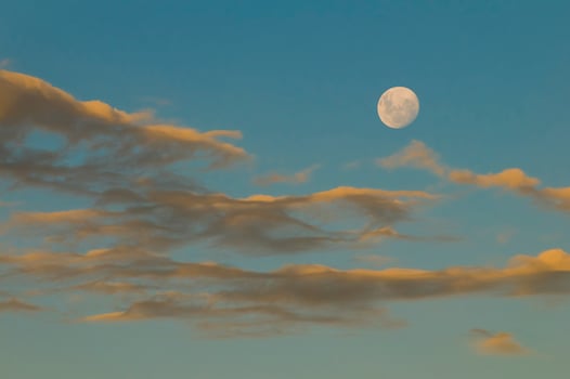 a full moon is seen in the sky above clouds photo