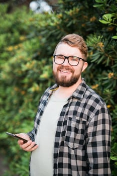 Laughing attractive man wearing hat over green tree background - emotion and vacation travel holidays concept photo
