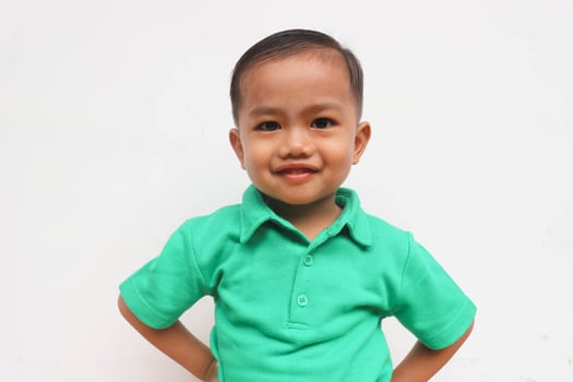 Portrait of a cute little Asian boy standing and smiling while looking at camera, on the white background photo