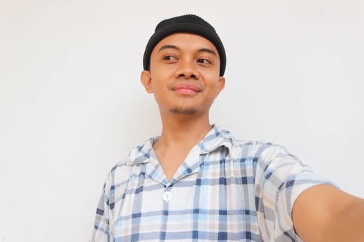 Smiling adult man wearing pajamas and beanie cap glancing to sideways to look something. Isolated on a white background photo