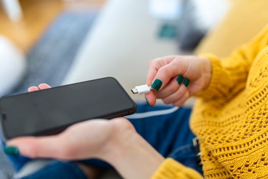 Woman hands plugging a charger in a smart phone. Woman using smartphone with powerbank, charging power to smart phone. Woman charging battery on mobile phone at home photo