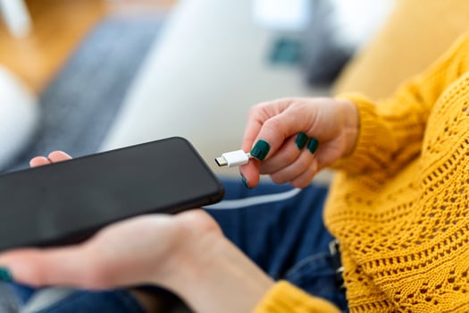 Woman hands plugging a charger in a smart phone. Woman using smartphone with powerbank, charging power to smart phone. Woman charging battery on mobile phone at home photo