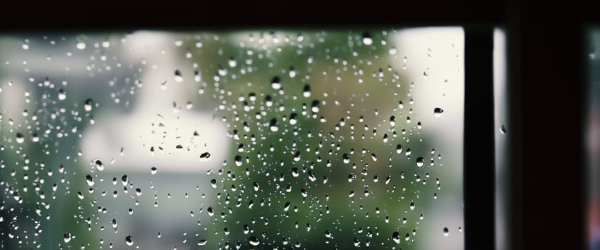 Rain drop on window glass of coffee shop and blurry city life background. Rainy season and blurry people city day life or bokeh night lights outside window. Coffee shop window covered with rain water photo