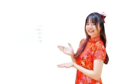 Cute Asian girl with long hair who wears a red Cheongsam dress in Chinese new year theme while she shows her hand to present something on a red background. photo