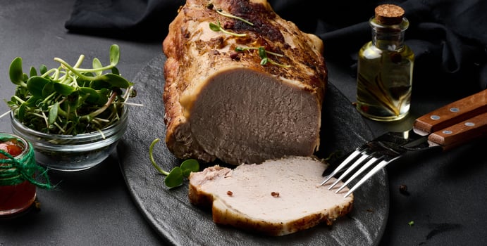 Baked piece of pork balyk on the table with spices. Tenderloin cut into pieces photo