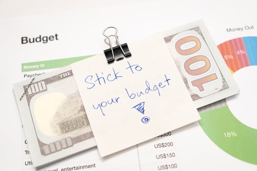Dollars cash money with text written note STICK TO YOUR BUDGET. concept of financial planning to save money by spending less. Finance and business concept. photo