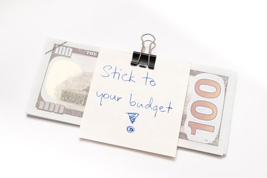Dollars cash money with text written note STICK TO YOUR BUDGET. concept of financial planning to save money by spending less. Finance and business concept. photo