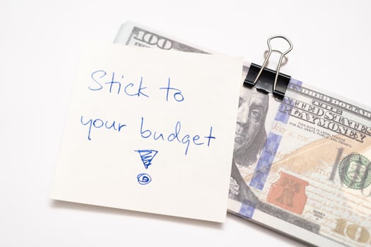 Dollars cash money with text written note STICK TO YOUR BUDGET. concept of financial planning to save money by spending less. Finance and business concept. photo