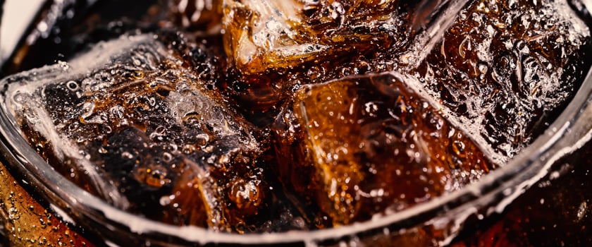 Cola with Ice. Close up of the ice cubes in cola water. Texture of carbonate drink with bubbles in glass. Cola soda and ice splashing fizzing or floating up to top of surface. Cold drink background. photo