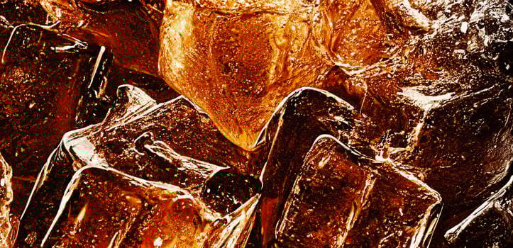 Cola with Ice. Close up of the ice cubes in cola water. Texture of carbonate drink with bubbles in glass. Cola soda and ice splashing fizzing or floating up to top of surface. Cold drink background. photo