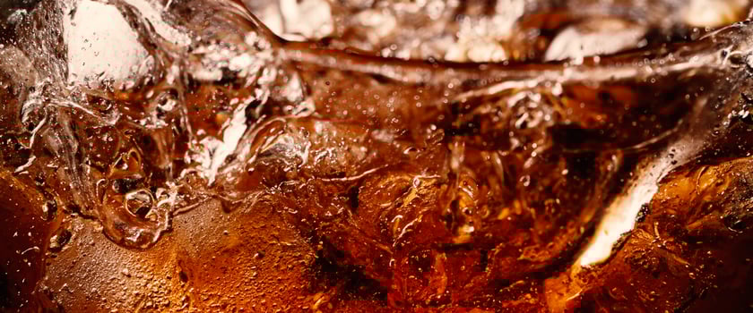 Splashing of Cola and Ice. Cola soda and ice splashing fizzing or floating up to top of surface. Close up of ice in cola water. Texture of carbonate drink with bubbles in glass. Cold drink background photo