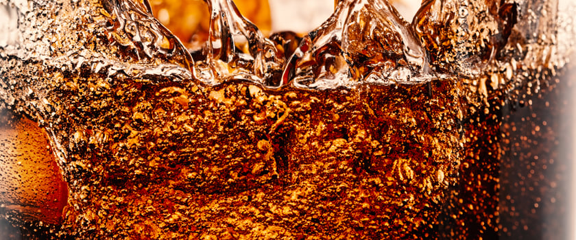 Splashing of Cola and Ice. Cola soda and ice splashing fizzing or floating up to top of surface. Close up of ice in cola water. Texture of carbonate drink with bubbles in glass. Cold drink background photo
