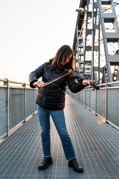attractive middle aged woman playing an electric violin outdoors photo
