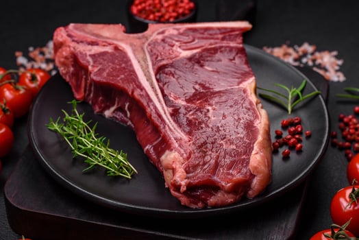 Raw juicy beef t-bone steak with salt, spices and herbs photo