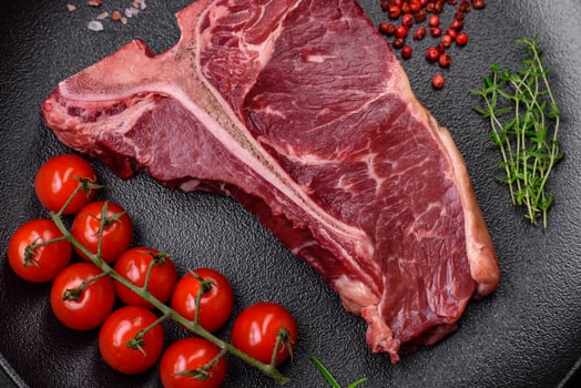 Raw juicy beef t-bone steak with salt, spices and herbs photo