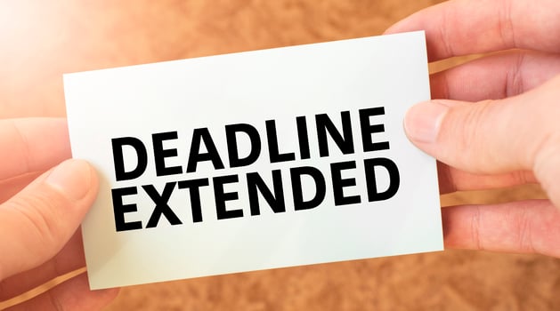 DEADLINE EXTENDED word inscription on white card paper sheet in hands of a businessman. recap concept. red and white paper photo