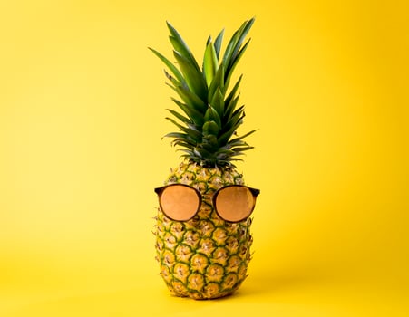 Tropical pineapple with sunglasses in summer season, beach vacation concept - yellow background photo