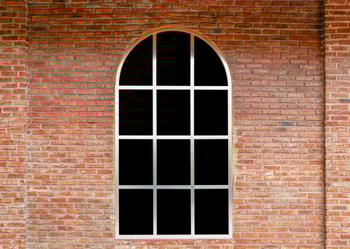Curve window with black glass on brick wall photo