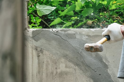 Hand of worker using hammer smashing and demolish on brick wall at construction site photo