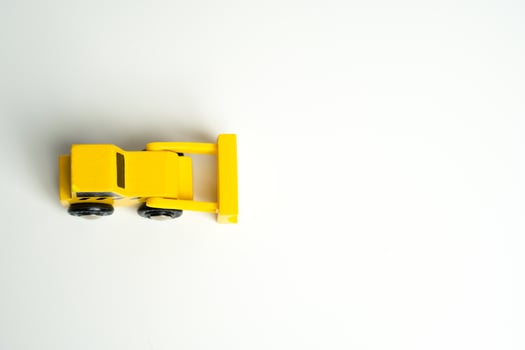 Yellow toy bulldozer, top view copy space. Metaphor to remove something, demolish. Construction works. Clearing and leveling the land. Building destruction. Take down Illegal construction. Industry photo