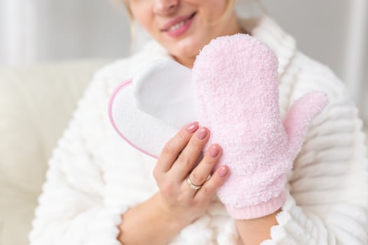 Excited joyful young woman wrapped head in towel holding dry brush shower sponge and doing spa procedure photo
