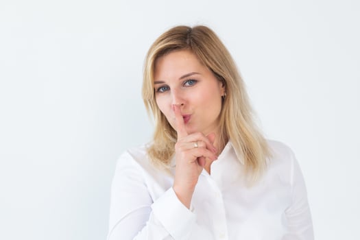 Beautiful young Caucasian woman isolated on white studio background hold finger at lips ask be silent quiet. Millennial female look at camera tell share mystery, announce secret sale or discount photo