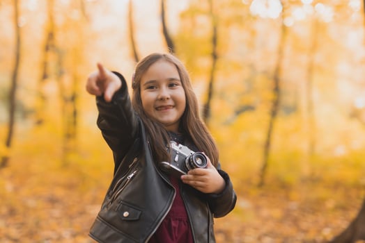 Child girl using an old-fashioned camera in autumn nature. Photographer, fall season and leisure concept. photo