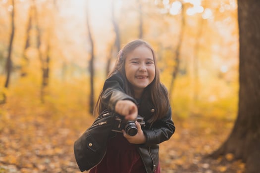 A little girl take a photo with old retro camera in autumn nature. Leisure and hobby concept.