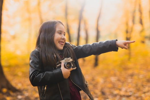 Child girl using an old-fashioned camera in autumn nature. Photographer, fall season and leisure concept. photo