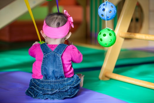 Beautiful ten months baby girl playing with colorful balls. Early stimulation for toddlers concept. photo