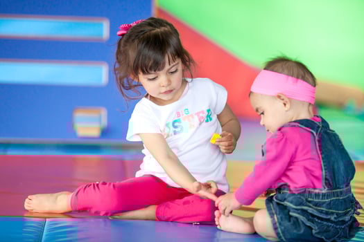 Beautiful small girl playing with her ten months baby girl sister. Early stimulation for toddlers and children concept. photo