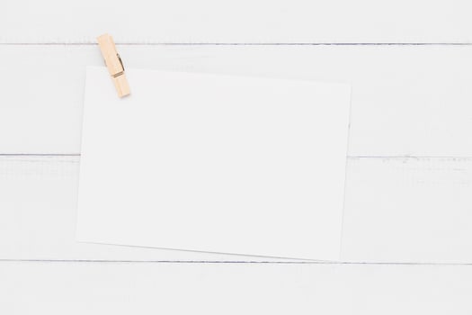 White paper card with wooden clamp on white table background for wedding invitation card design and writing or printing on. photo