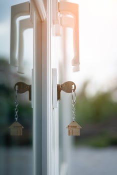 Landlord key for unlocking house is plugged into the door. Second hand house for rent and sale. keychain is blowing in the wind. mortgage for new home, buy, sell, renovate, investment, owner, estate photo