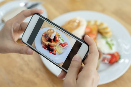 restaurant owner takes a picture of the food on the table with a smartphone to post on a website. Online food delivery, ordering service, influencer, review, social media, share, marketing, interest. photo
