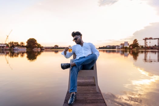 young man of Pakistani ethnicity drinking beer sitting on the quayside of a river port photo