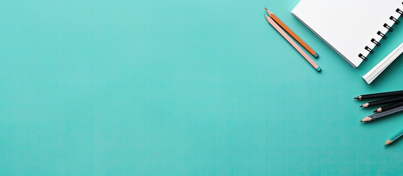 A notebook, pencils, and a pair of scissors on a turquoise background created with technology photo