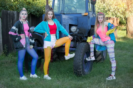 Three country girls dressed in the style of the 90s stand by the tractor. photo