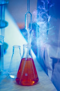 Glass laboratory flasks with chemical substance and magic glow. Making a magic potion. photo
