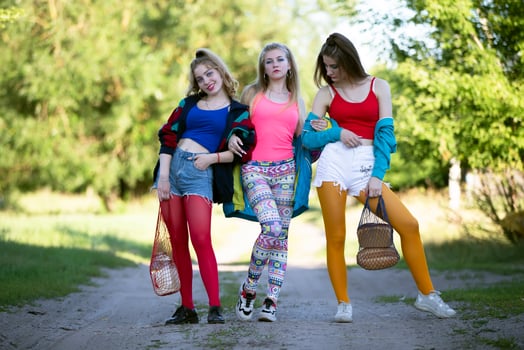 Three beautiful country girls dressed in the style of the nineties are walking along the road. photo