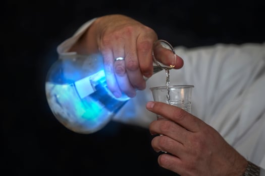 Chemical flask with a blue solution and a mystical glow in the hands of a laboratory assistant. Experiences and experiments. photo