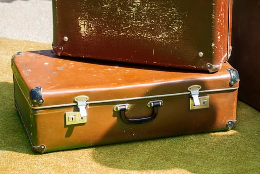 Old shabby brown suitcases on a green surface. photo