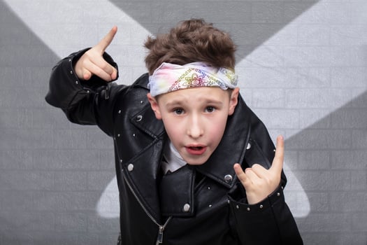 Portrait of a heavy metal boy in sunglasses. Cute teenager in a leather jacket doing a rock and roll sign photo