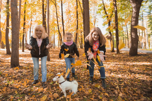 Grandmother and mother with granddaughter throw up fall leaves in autumn park and having fun. Generation, leisure and family concept. photo